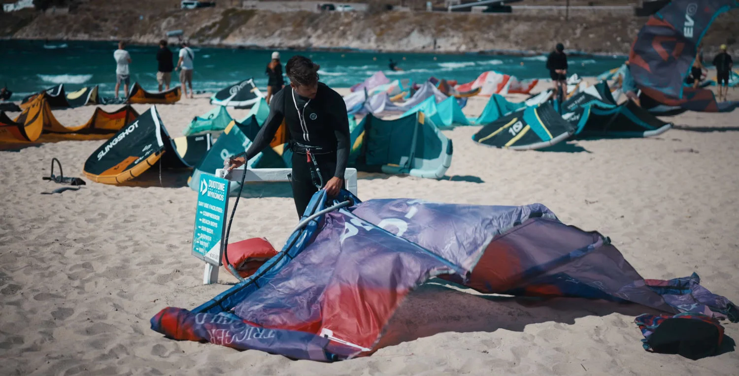 Rubens debout sur la plage gonfle le bord d'attaque du kite F-One Trigger V3.